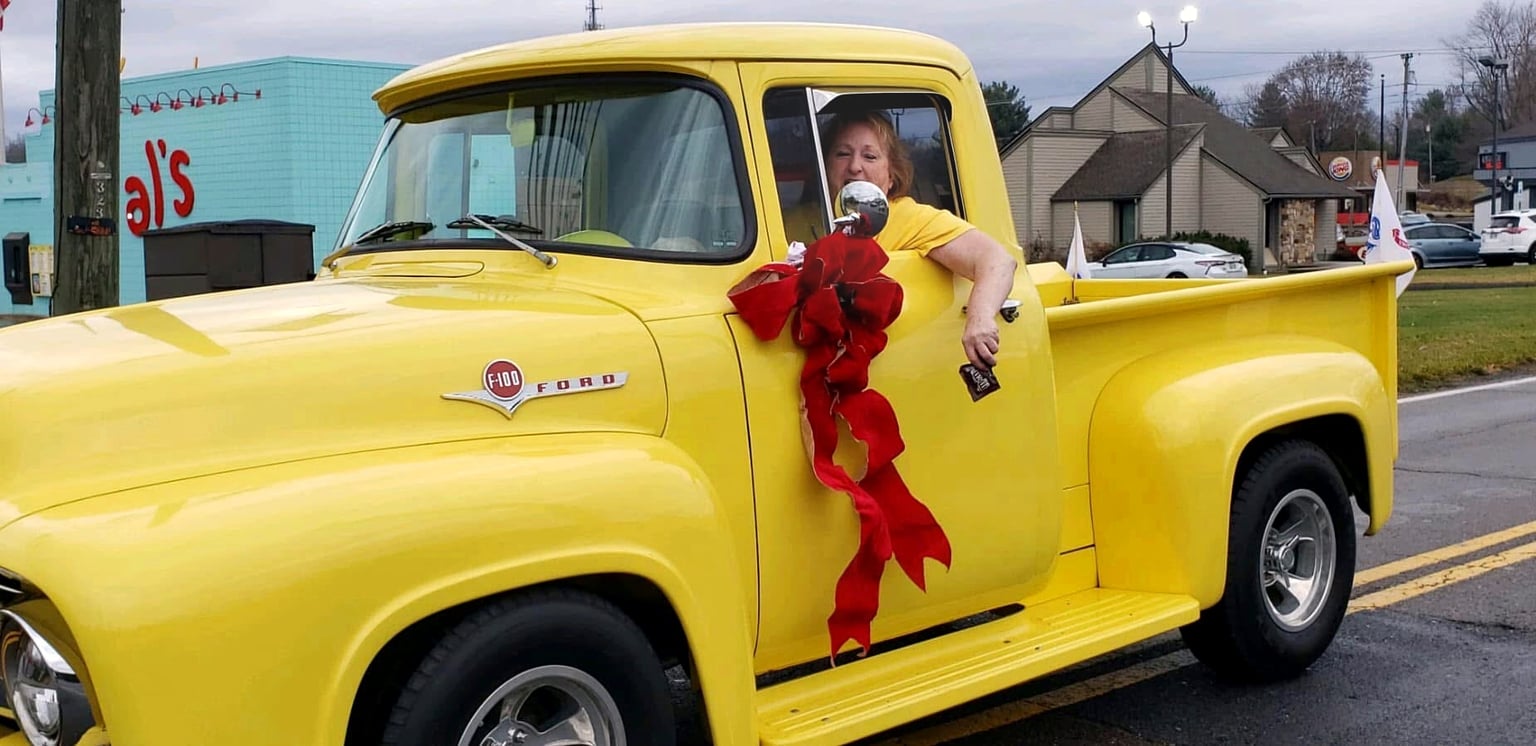 Joyce Crosswhite leaning out of her yellow Ford F-100 campaign truck during a local Christmas parade in Sullivan County